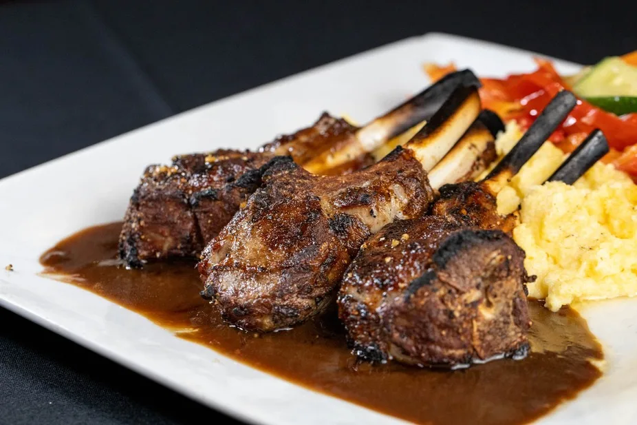 Close-up of charred lamb chops plated over creamy polenta
